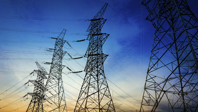 Sun setting behind the silhouette of electricity pylons